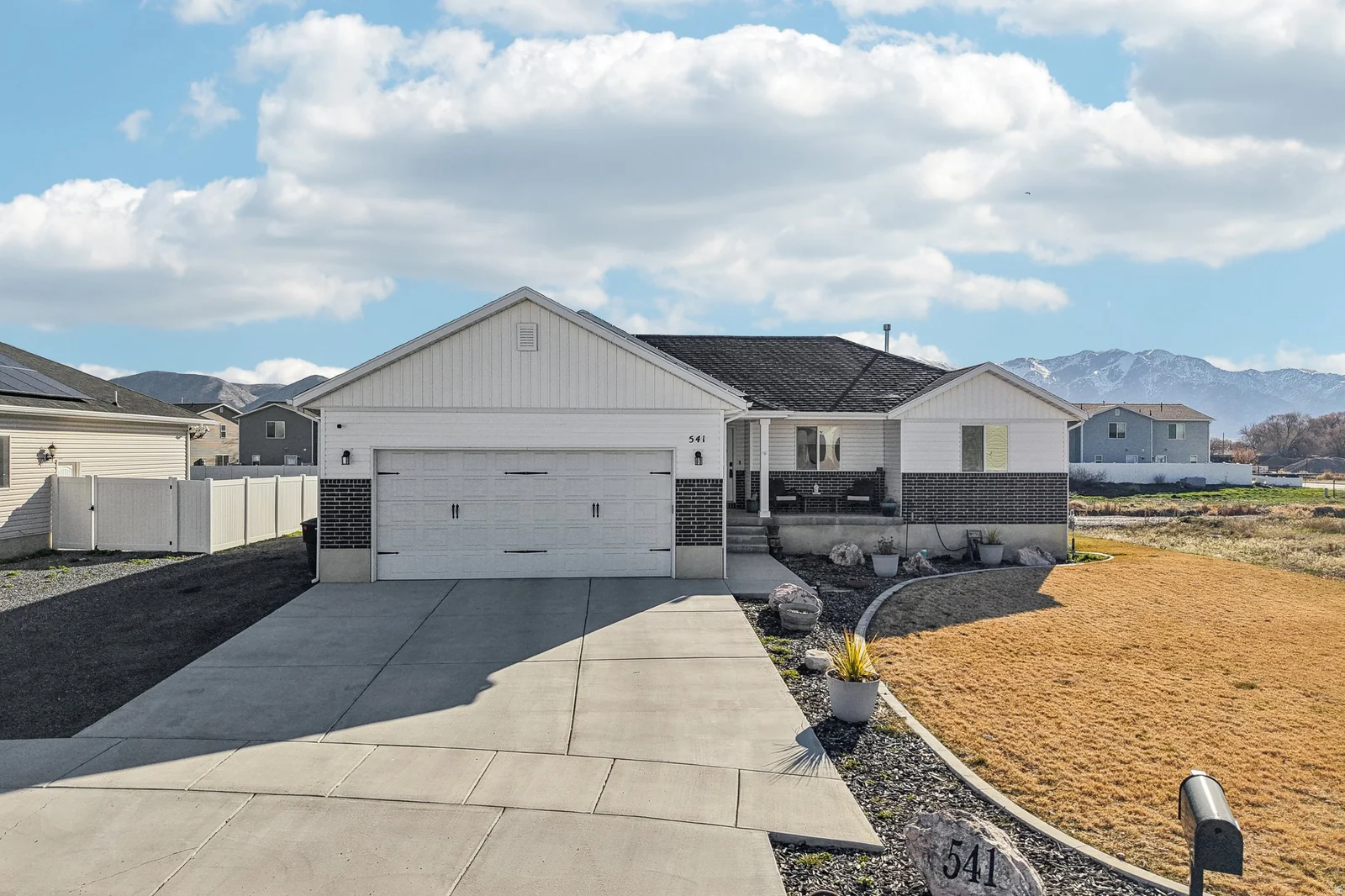 Single story home with concrete driveway, an attached garage, a mountain view, brick siding, and a porch