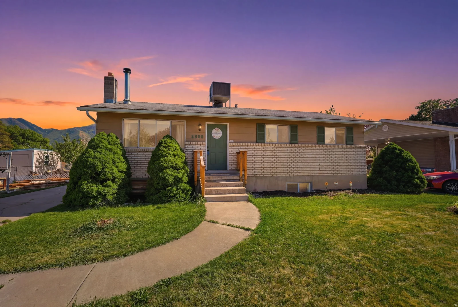 Single-story residence featuring a brick and siding exterior, a front entry with a green door, and a concrete walkway