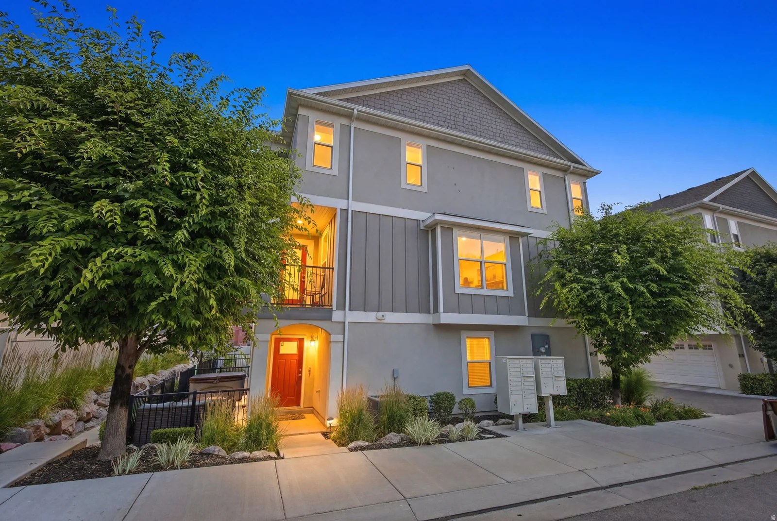 Multi-story residence featuring a gray exterior with vertical siding accents and a contrasting shingled gable roof