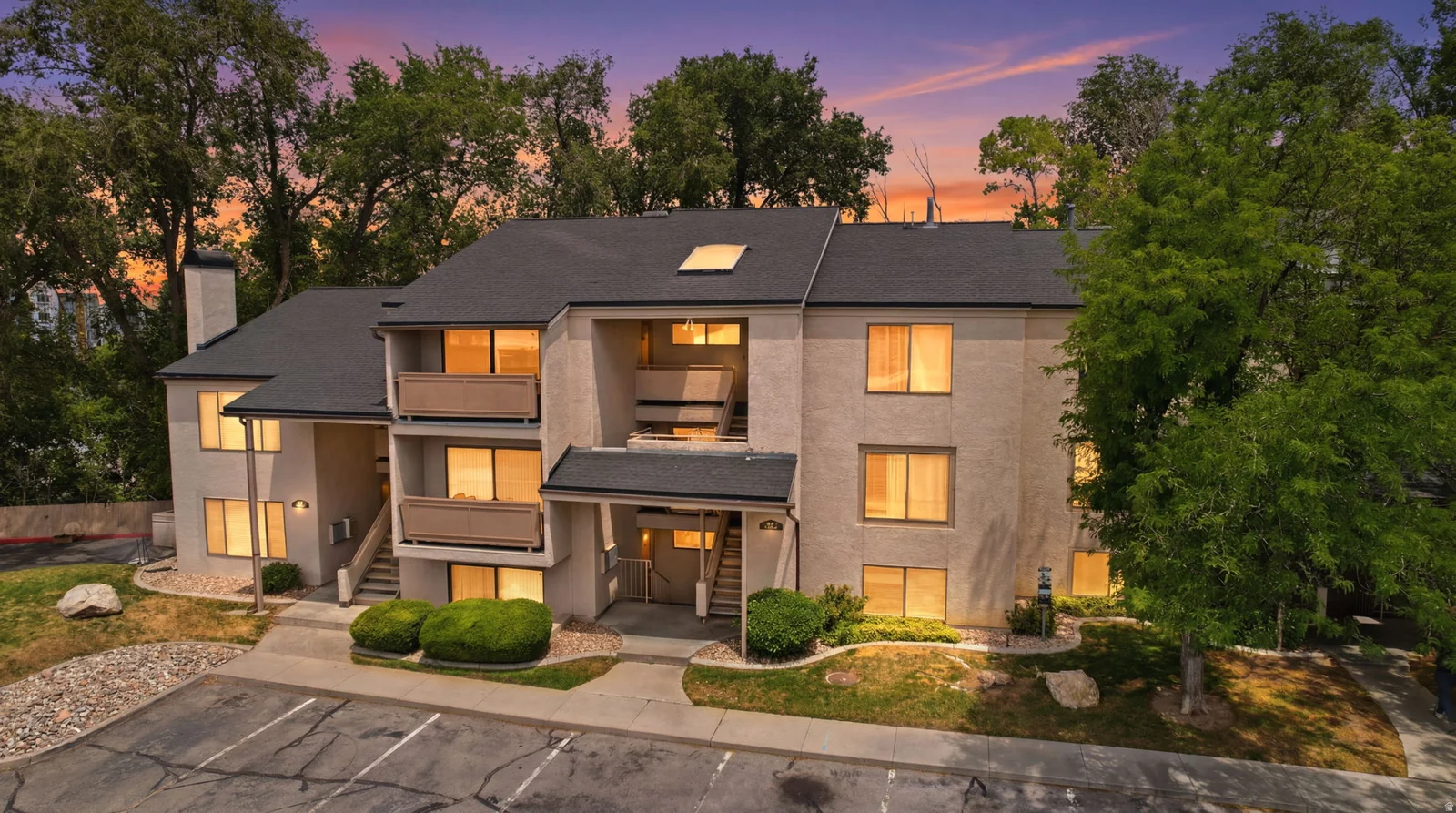 Multi-story building featuring balconies, multiple windows, a dark shingle roof, and a visible chimney