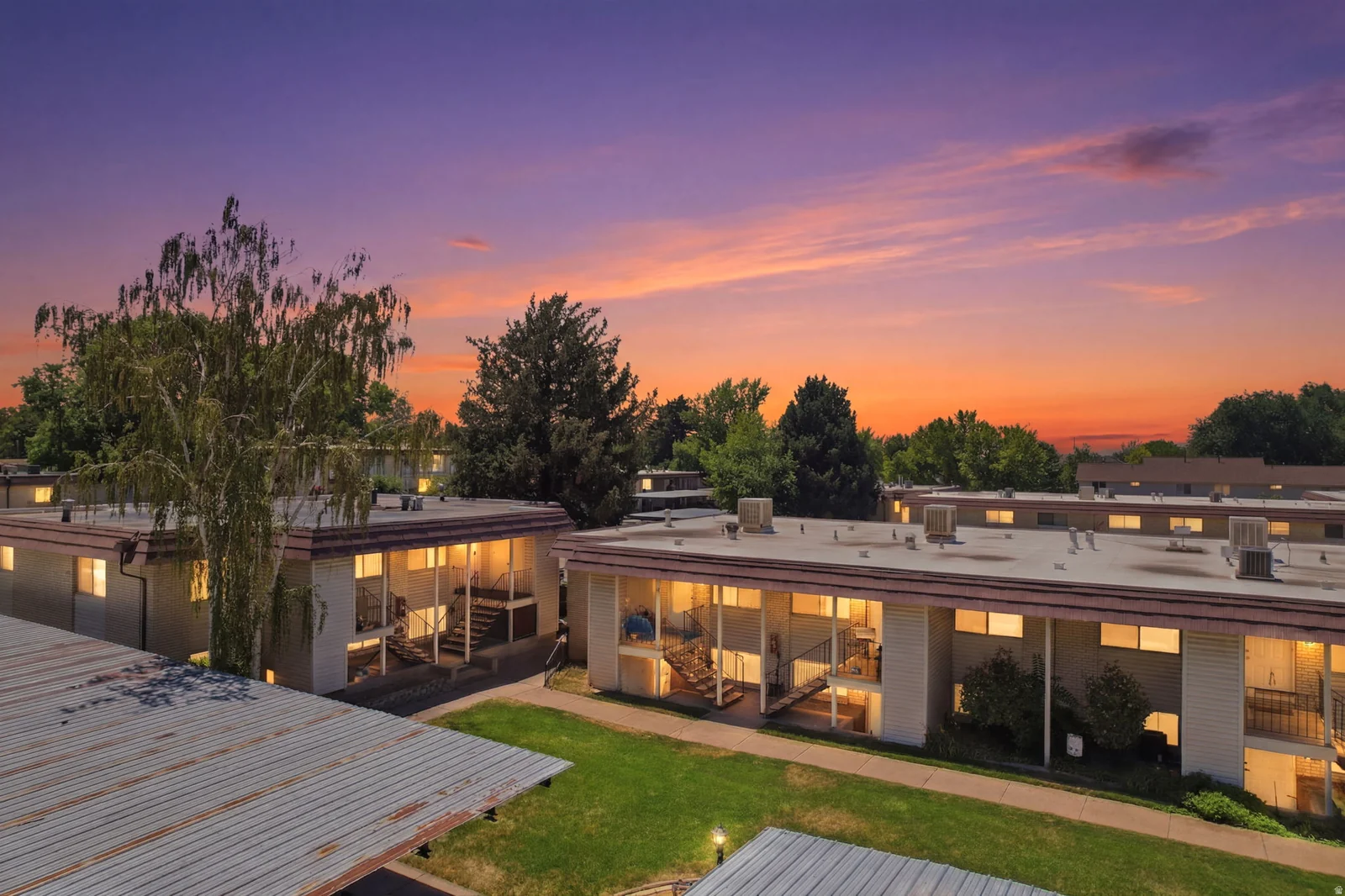 Multi-unit complex featuring neutral-toned siding, multiple windows, and a central green space
