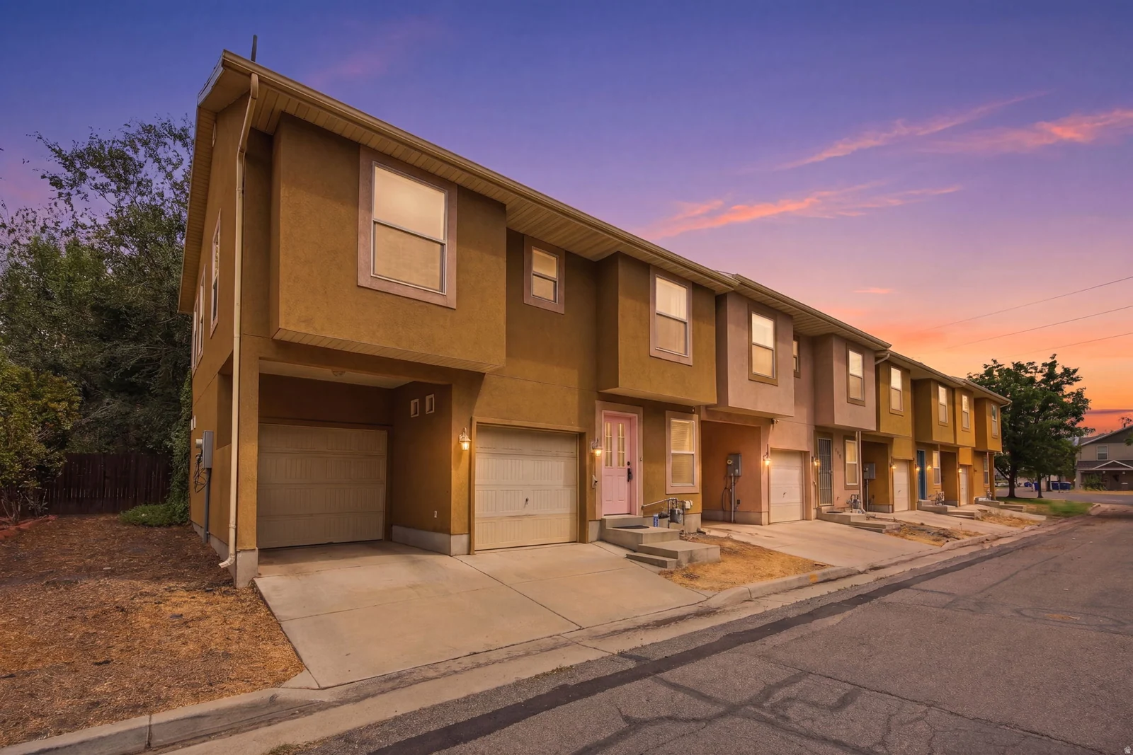 Stucco exterior townhome featuring an integrated garage and concrete driveway