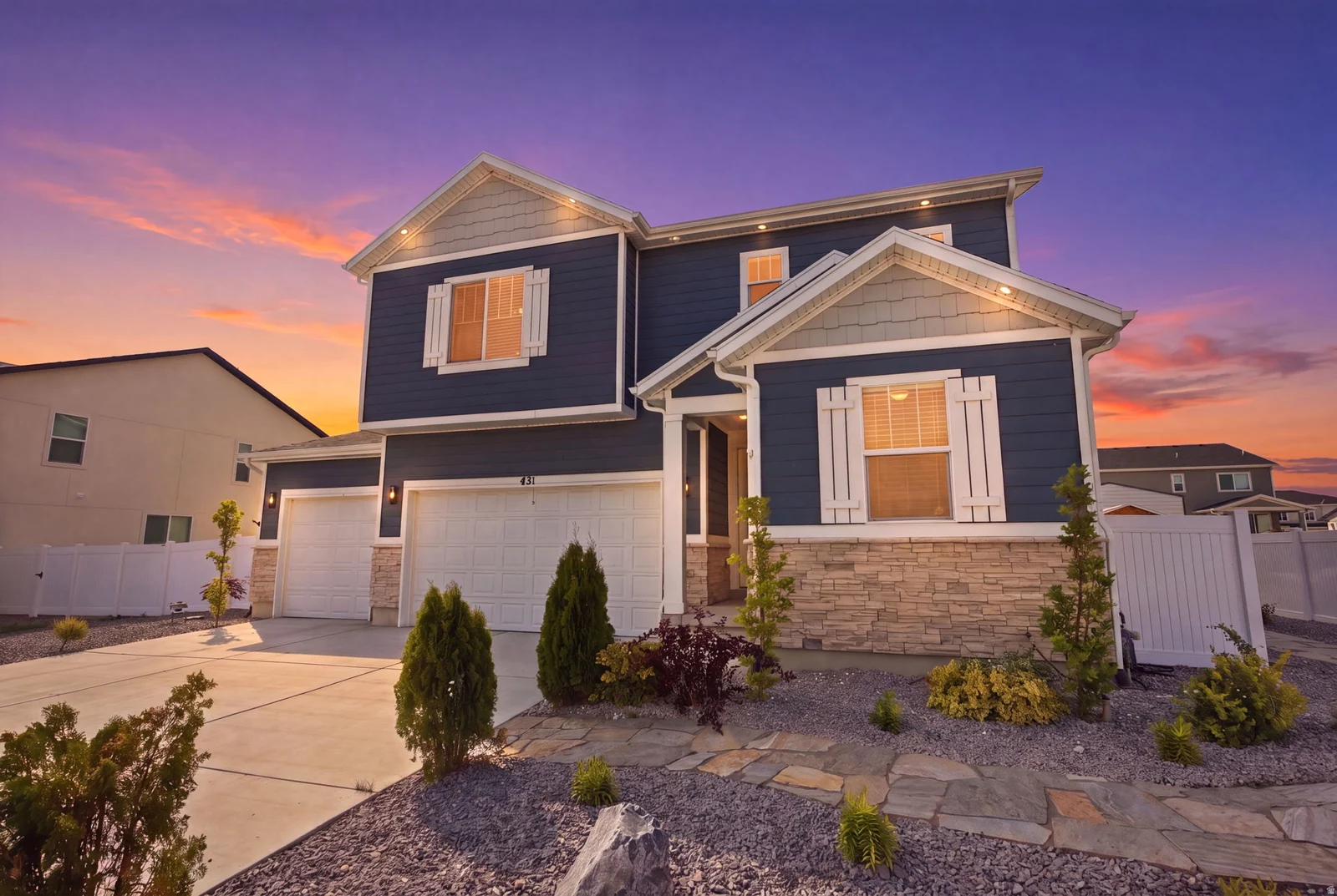 Two-story residence featuring a dark blue siding exterior with stone accents and a multi-car garage