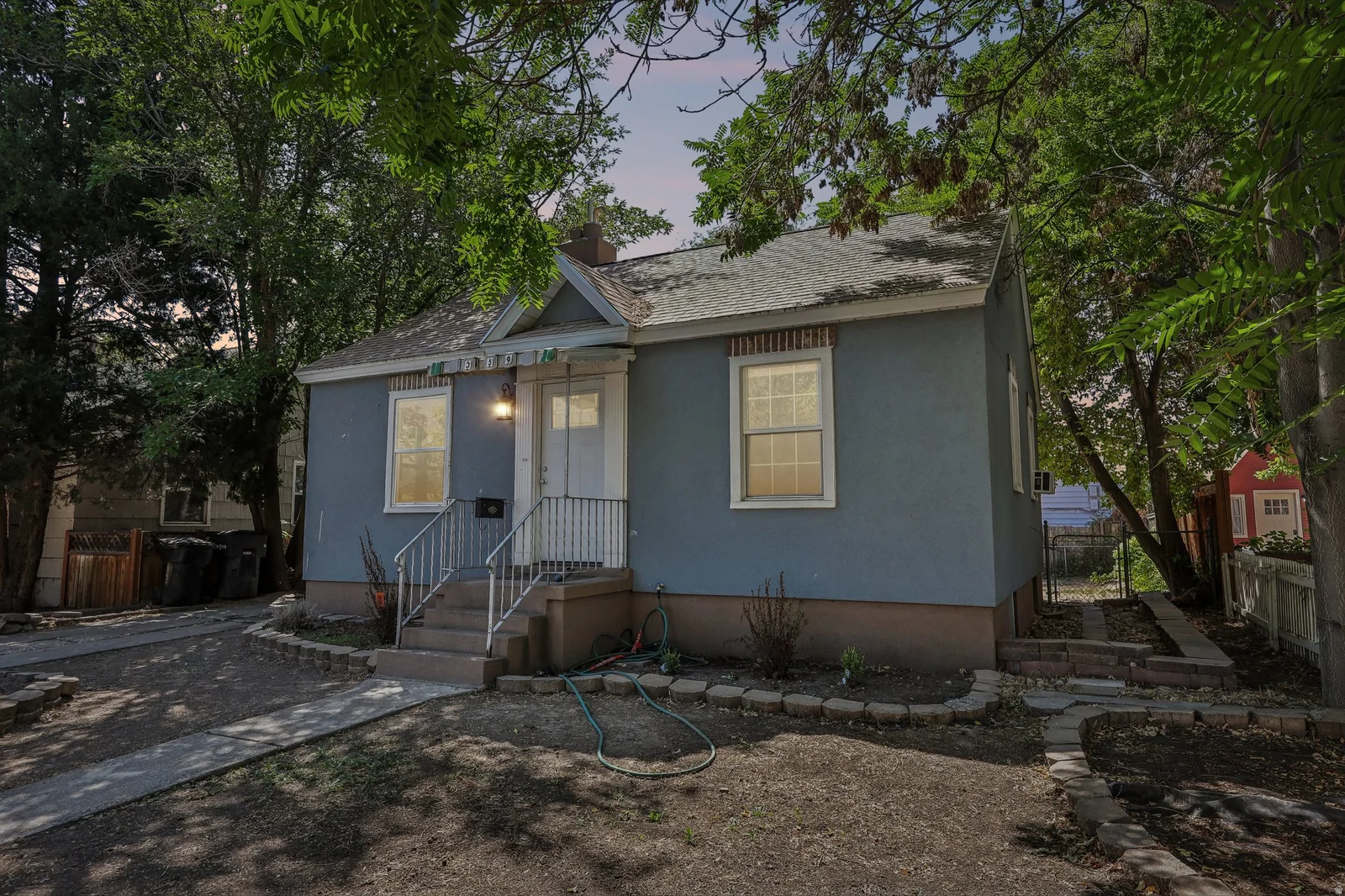 Stucco exterior with a pitched roof, front entry stairs with handrails, and a paved driveway