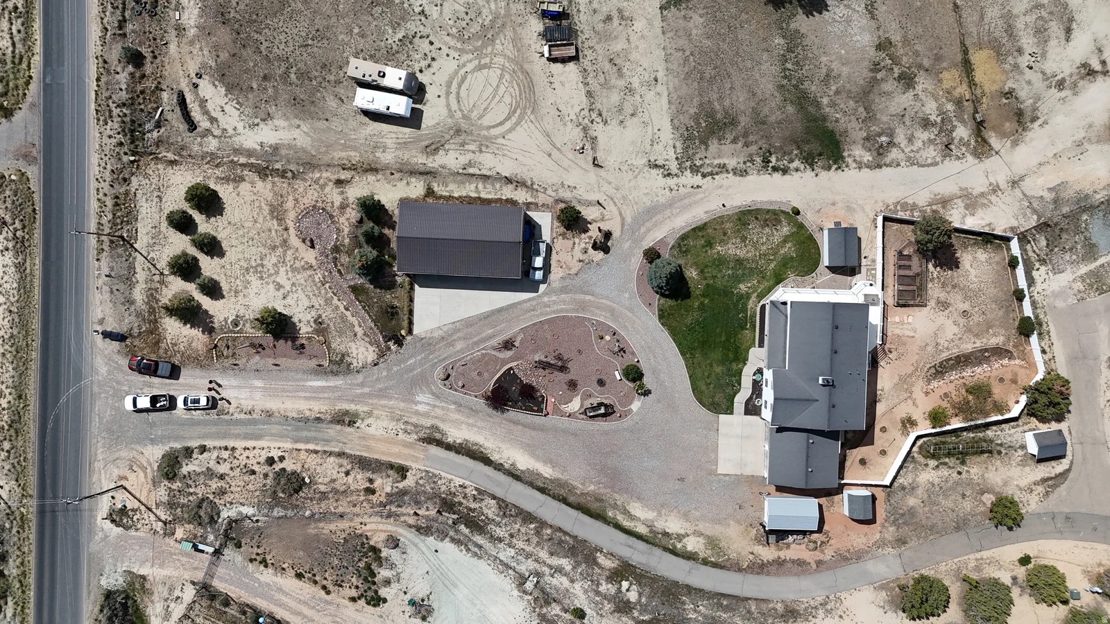 Expansive property featuring a paved driveway, detached garage, and multiple outbuildings