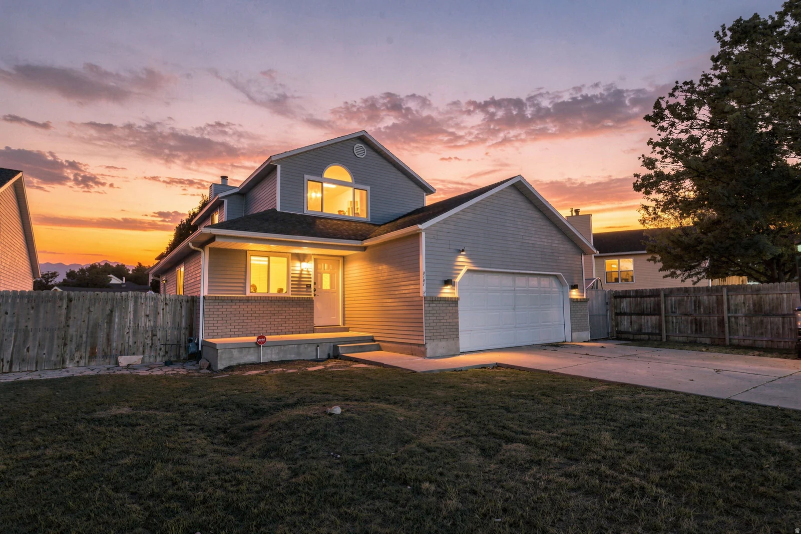 Two-story residence with gray siding, attached garage, and a concrete driveway