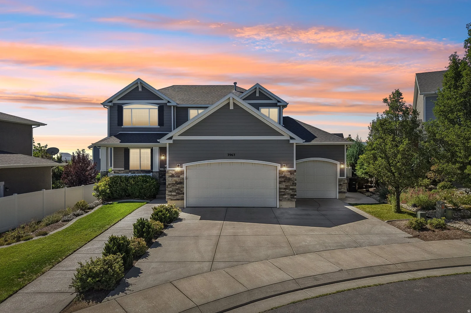 Two-story residence featuring a two-car garage, stone accents, and a concrete driveway