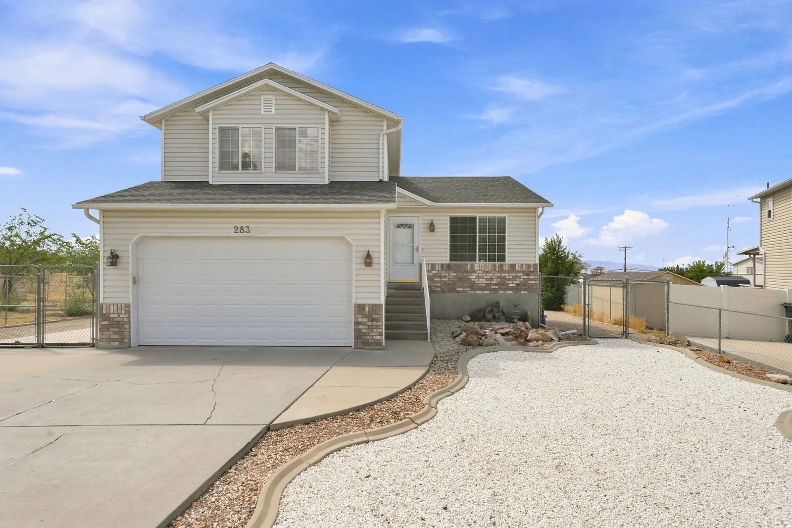 Two-story residence featuring light-colored siding, a two-car garage, and a covered front entry