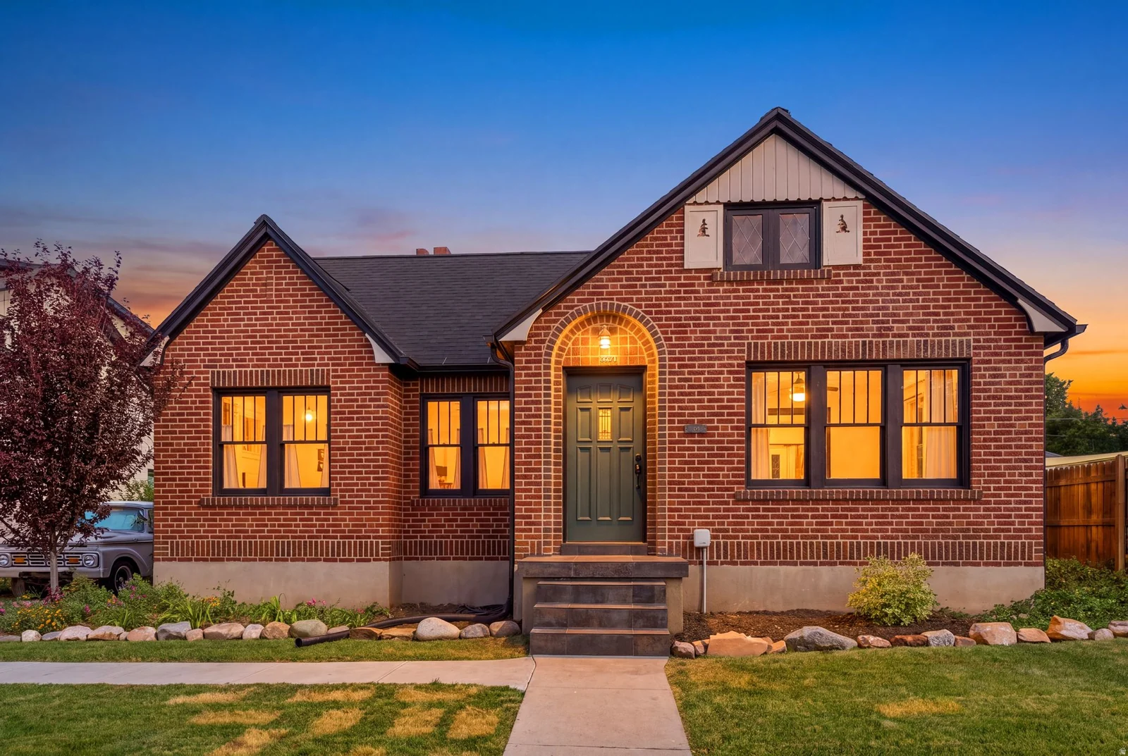 Brick exterior with a dark-pitched roof, arched entryway, and dark-framed windows