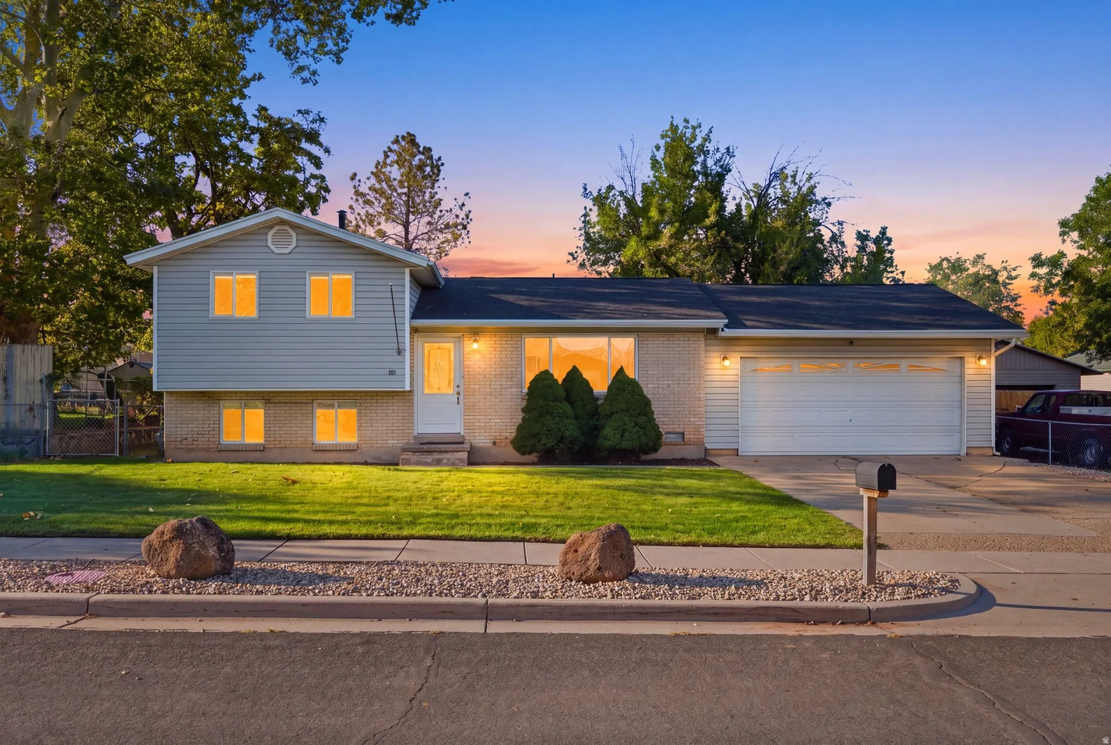 Traditional split-level exterior featuring light-colored siding and brick detailing